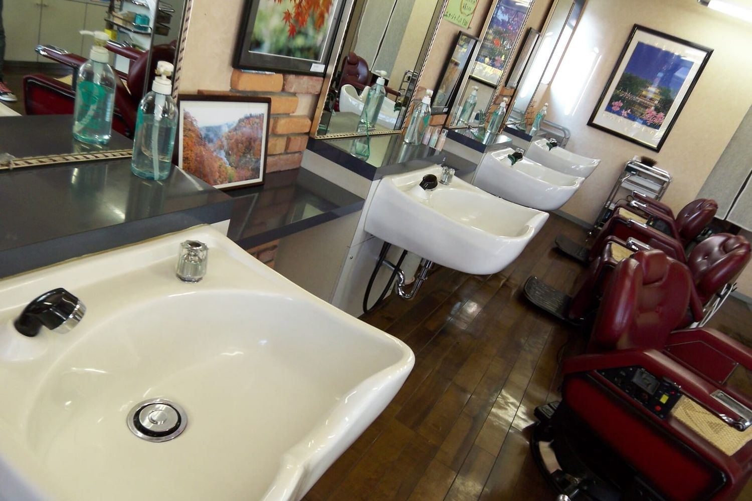 Leerer Friseursalon mit roten Bedienstühlen, Waschbecken und Spiegeln