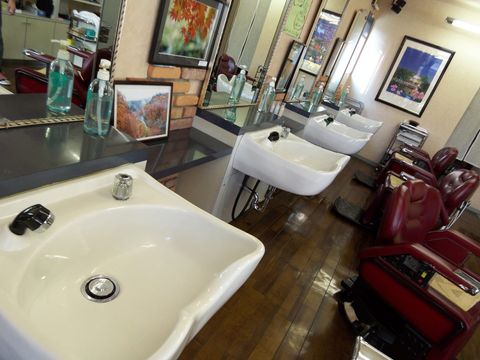 Leerer Friseursalon mit roten Bedienstühlen, Waschbecken und Spiegeln