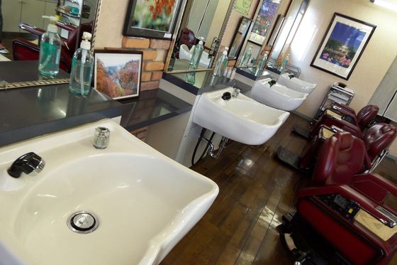 Leerer Friseursalon mit roten Bedienstühlen, Waschbecken und Spiegeln