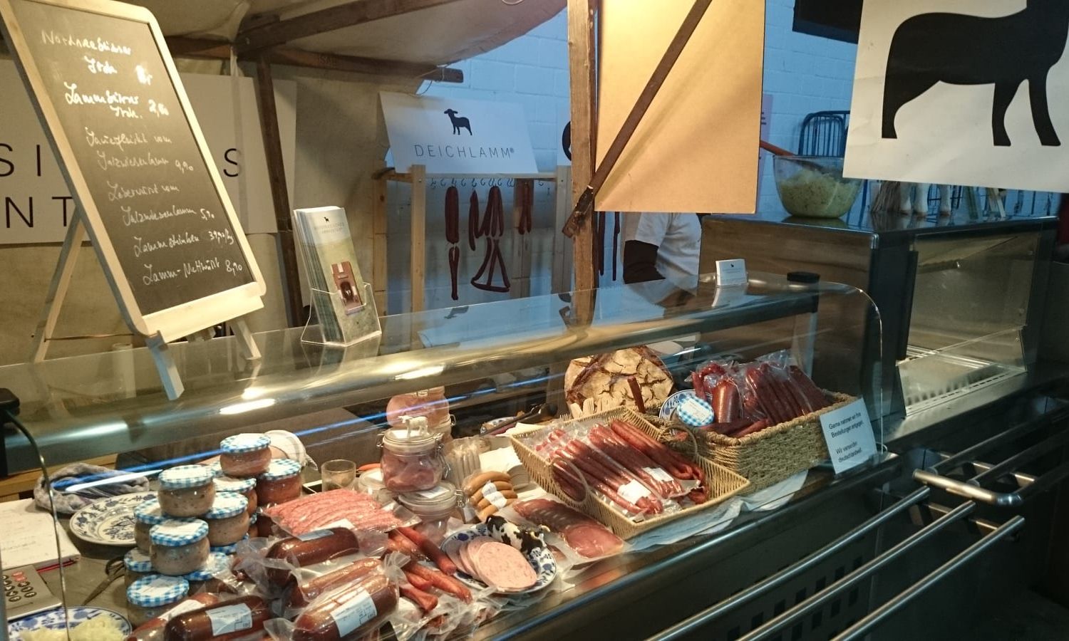 Marktstand mit Wurstwaren und Kreidetafel in der Markthalle Neun in Berlin-Kreuzberg