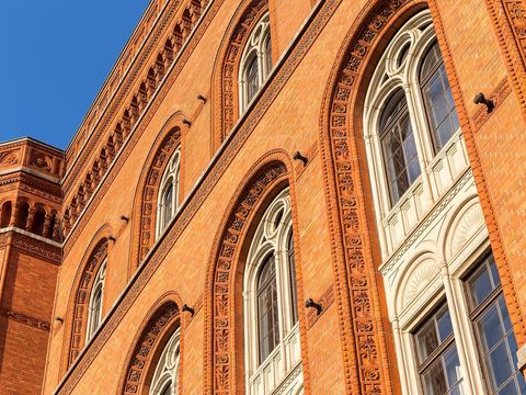 Ziegelfassade des Roten Rathauses in Berlin mit Rundbogenfenstern vor blauem Himmel