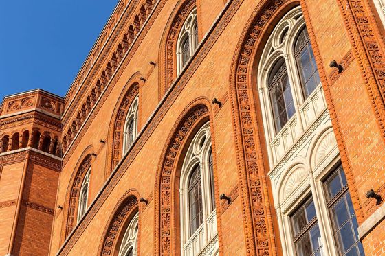 Ziegelfassade des Roten Rathauses in Berlin mit Rundbogenfenstern vor blauem Himmel