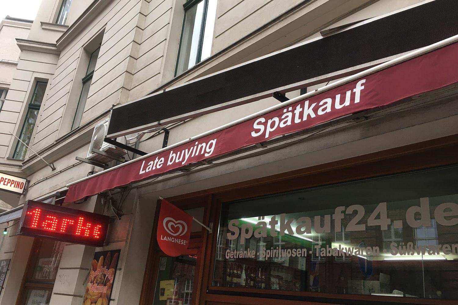 Ladenfront eines Spätkaufs in Berlin-Mitte mit roter Markise und Leuchtschrift
